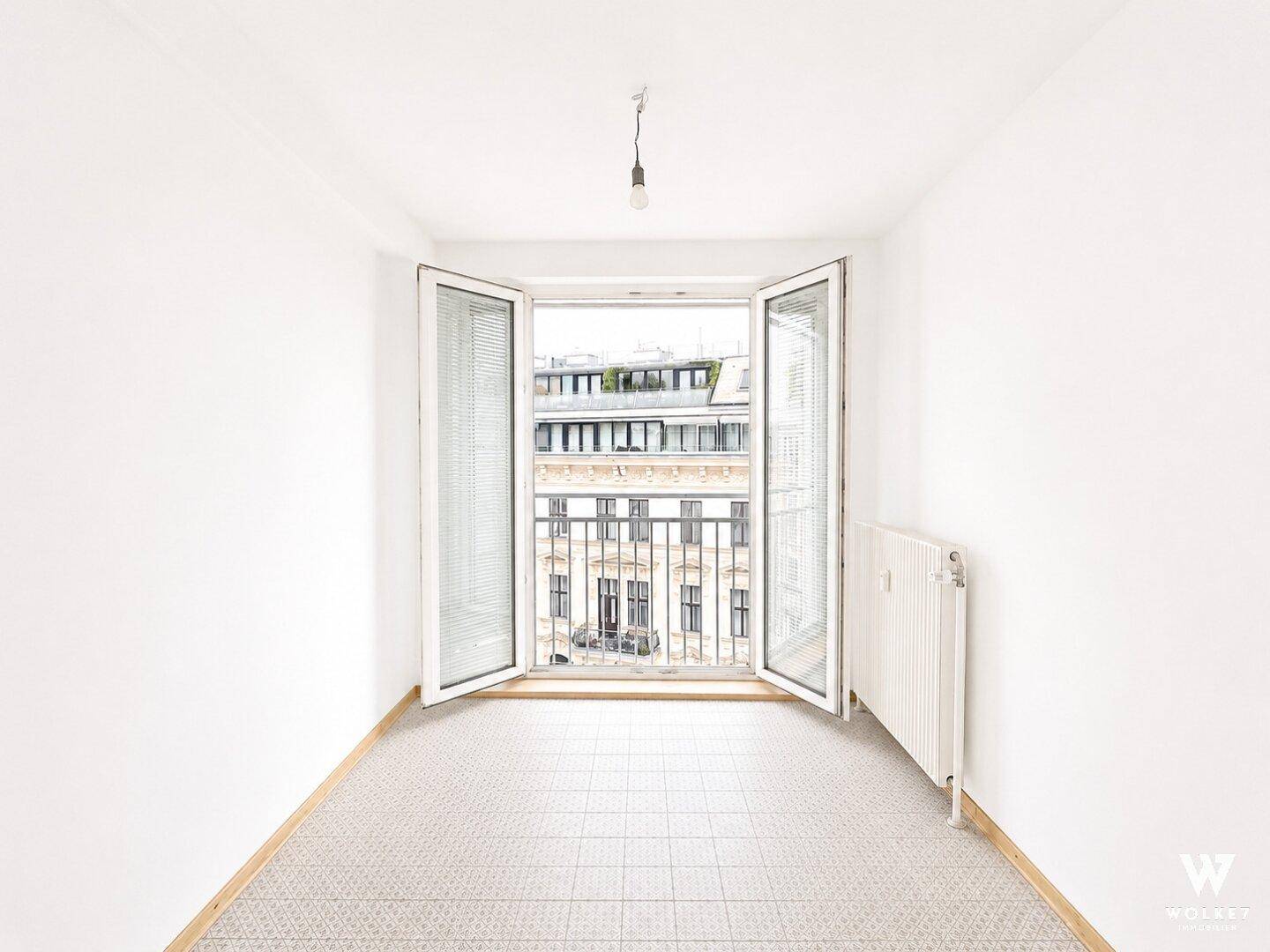 Leerer Raum mit großen Fenstertüren, die einen Blick auf die Stadt ermöglichen.
