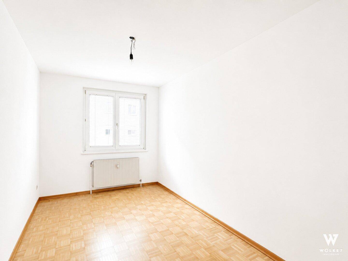 Heller, leerer Raum mit Parkettboden und Fenster, vielseitig nutzbar.