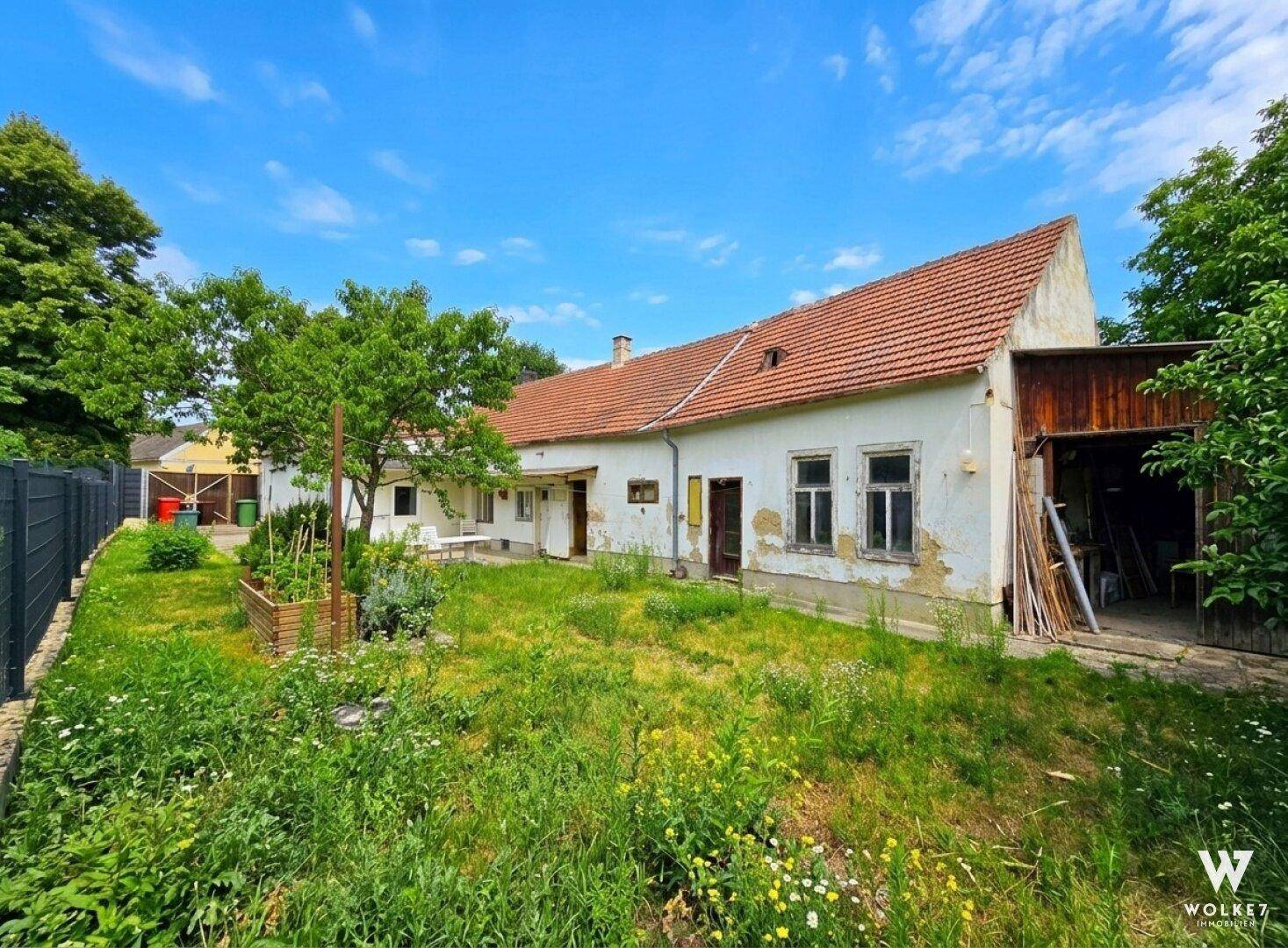Rückseite des Einfamilienhauses mit großem, naturbelassenem Garten und Nebengebäude.