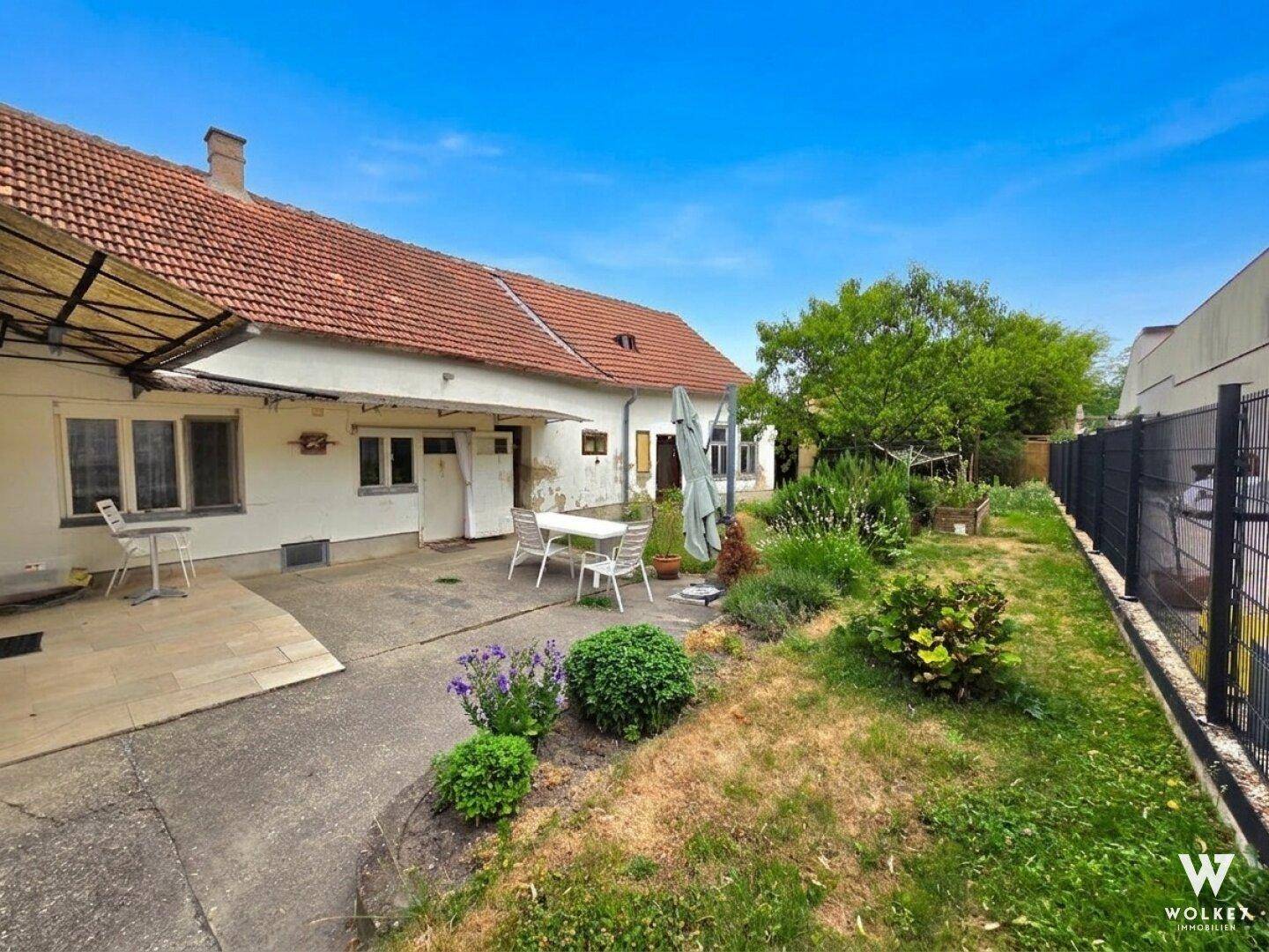 Gepflasterte Terrasse mit Gartenmöbeln und Blick auf den weitläufigen Gartenbereich.