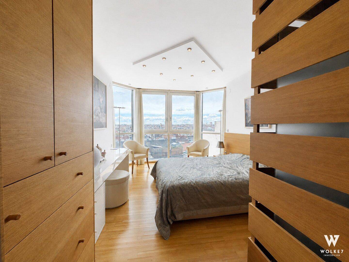 Schlafzimmer mit Panoramafenstern, Holzboden und Einbaumöbeln bietet weite Stadtblicke.