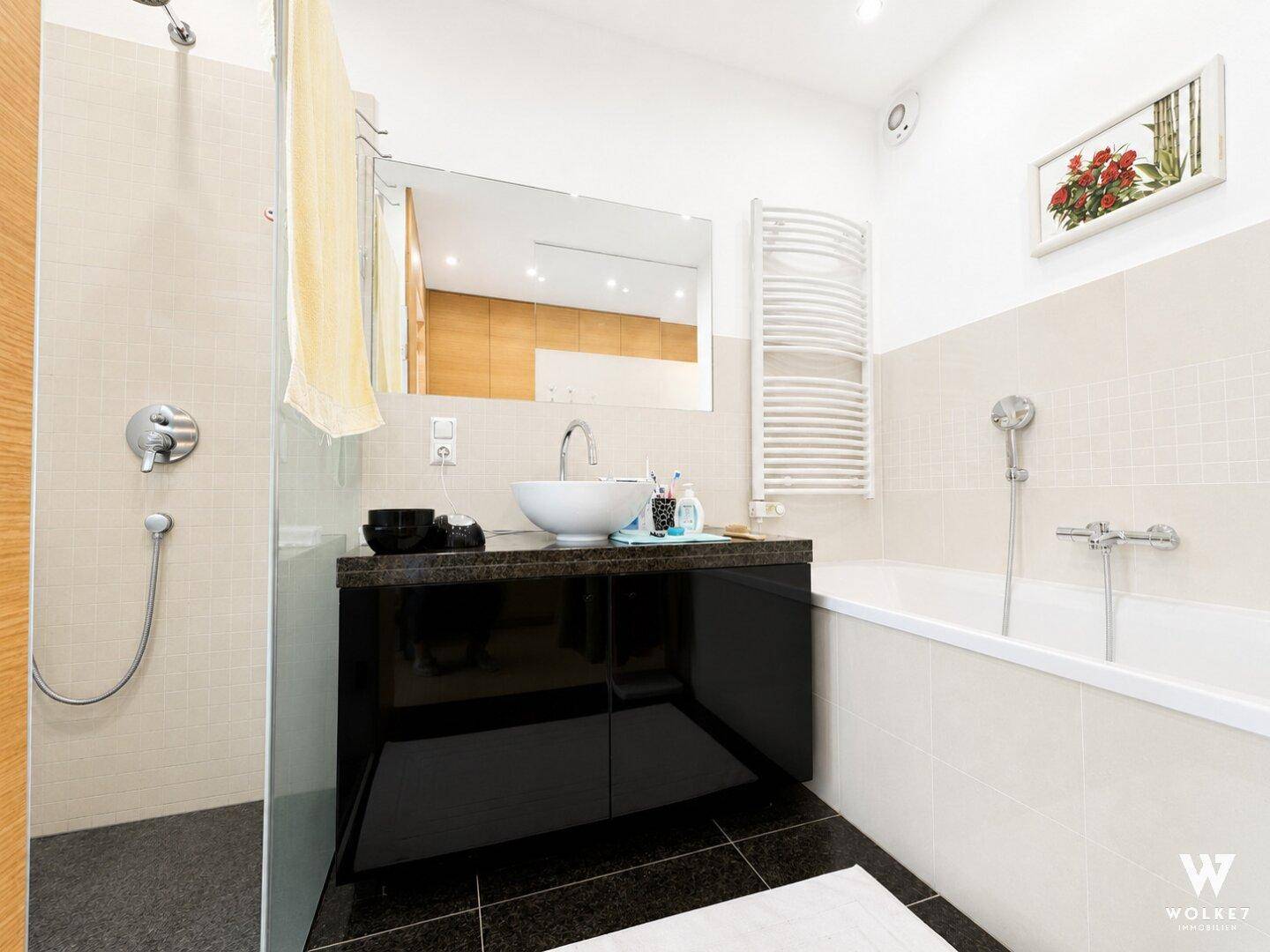 Modernes Badezimmer mit Dusche, Badewanne, Einzelwaschbecken und beheiztem Handtuchhalter.