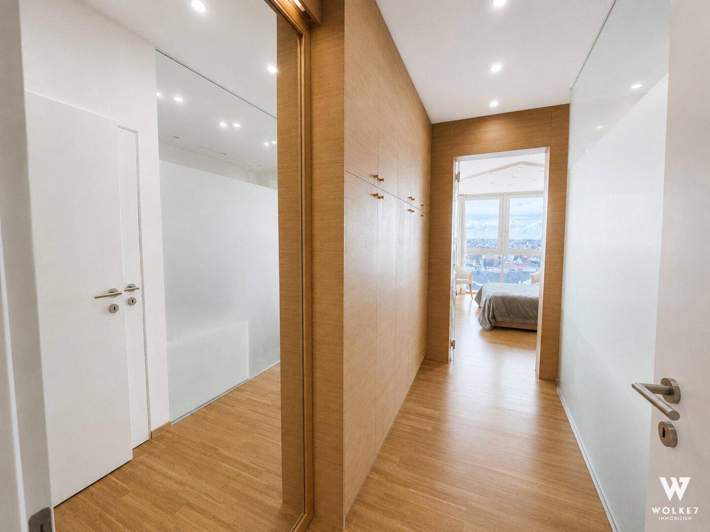 Heller Flur mit Holzwänden, Einbauschränken und Spiegel, der zum Schlafzimmer führt.