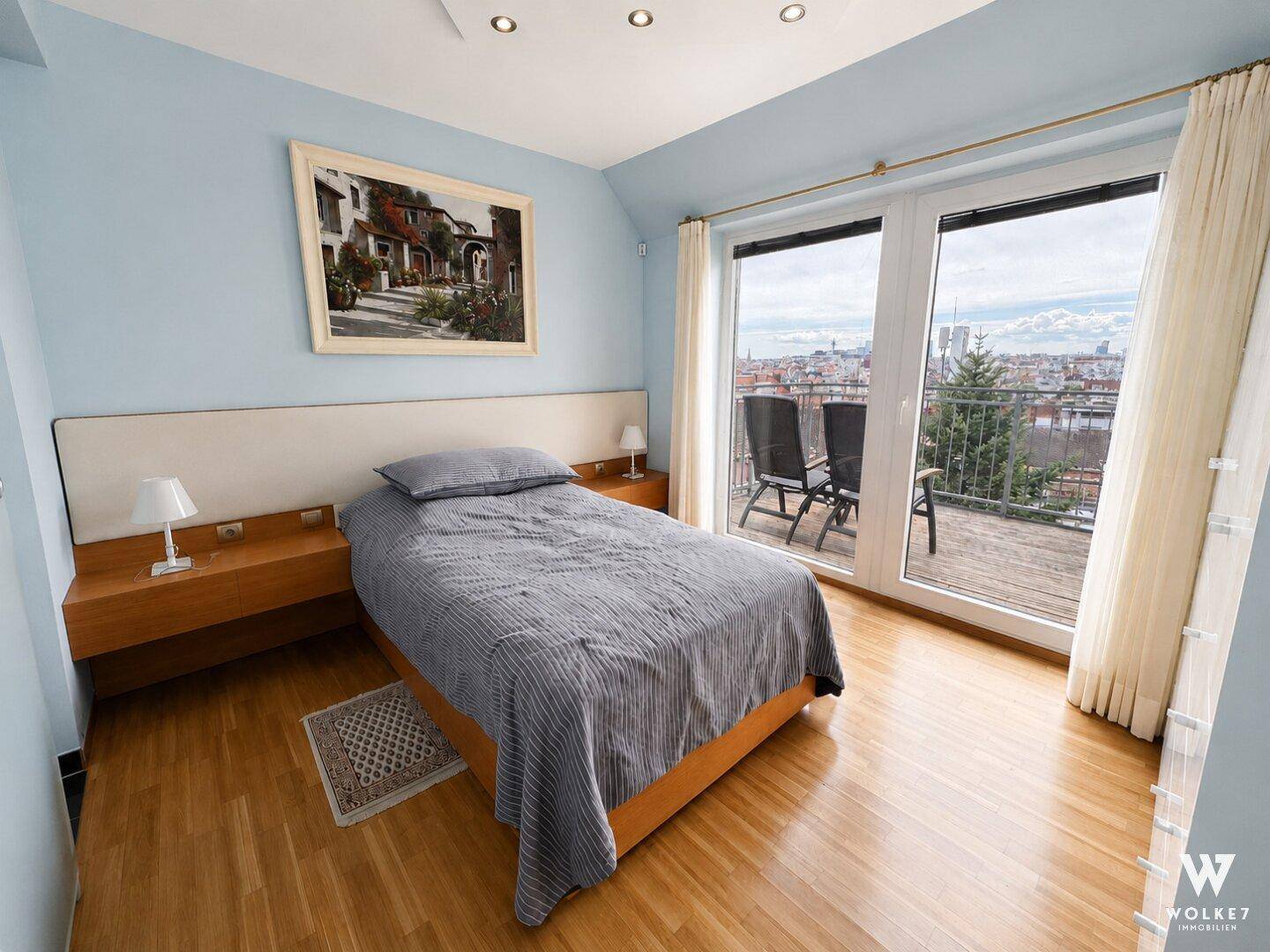 Schlafzimmer mit hellblauen Wänden, Holzboden und direktem Zugang zur Dachterrasse mit Stadtblick.