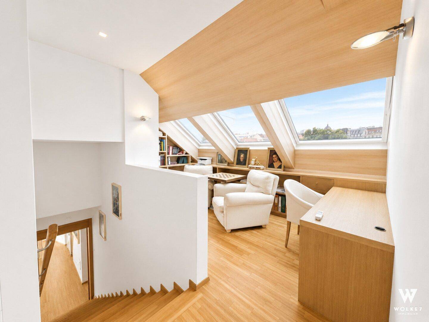 Helles Arbeitszimmer im Dachgeschoss mit Holzboden, Schreibtisch und großen Dachfenstern.