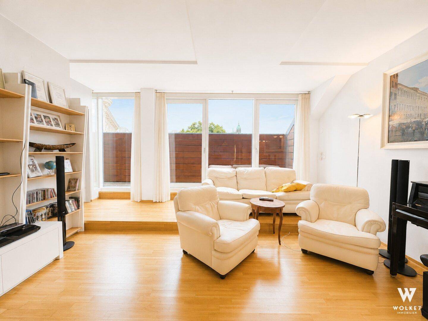 Gemütliches Wohnzimmer mit Holzboden, hellen Sofas und Zugang zu einer privaten Terrasse.