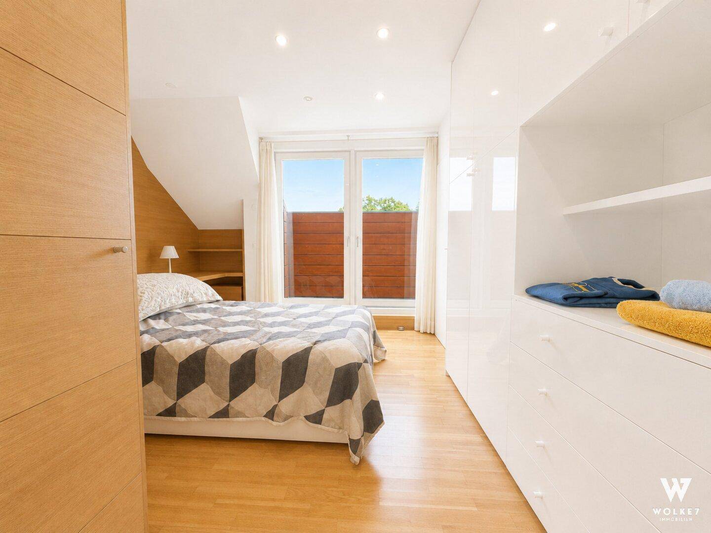 Helles Schlafzimmer mit integrierten weißen Kleiderschränken und Holzboden.