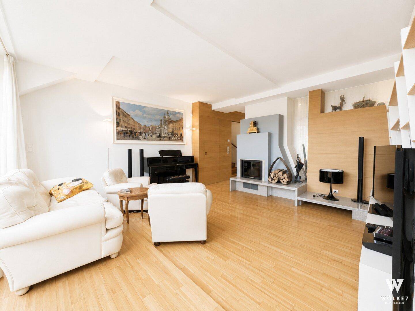 Gemütliches Wohnzimmer mit Kamin, Klavier und Holzboden, dekoriert mit Hirschgeweihen.