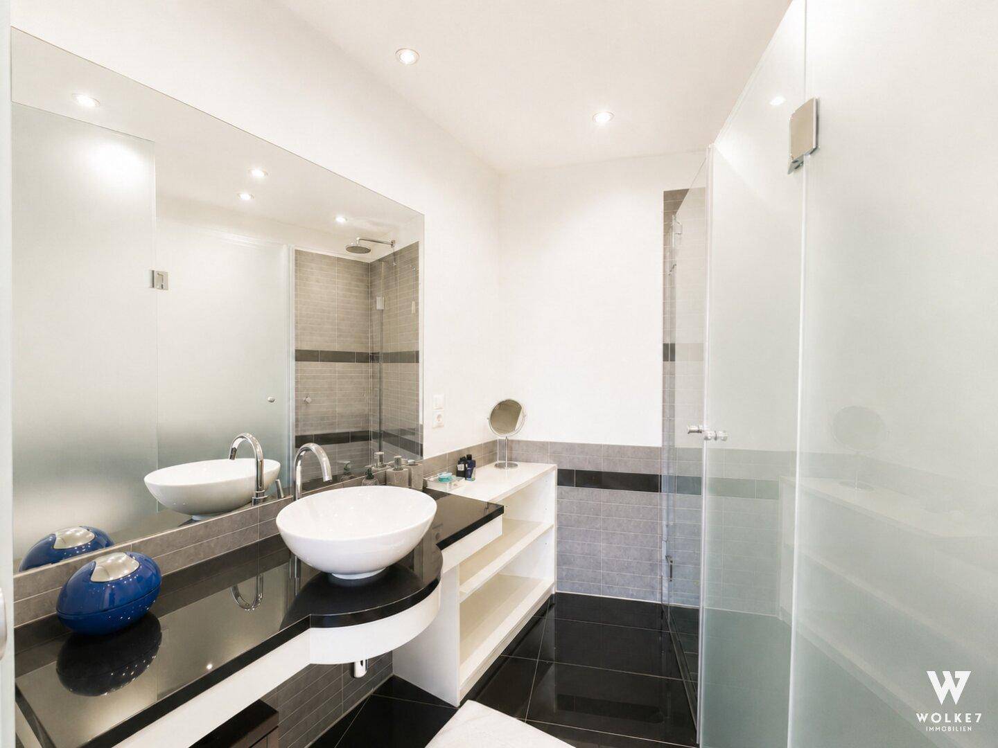 Modernes Badezimmer mit großer Dusche, Einzelwaschbecken und großem Spiegel.