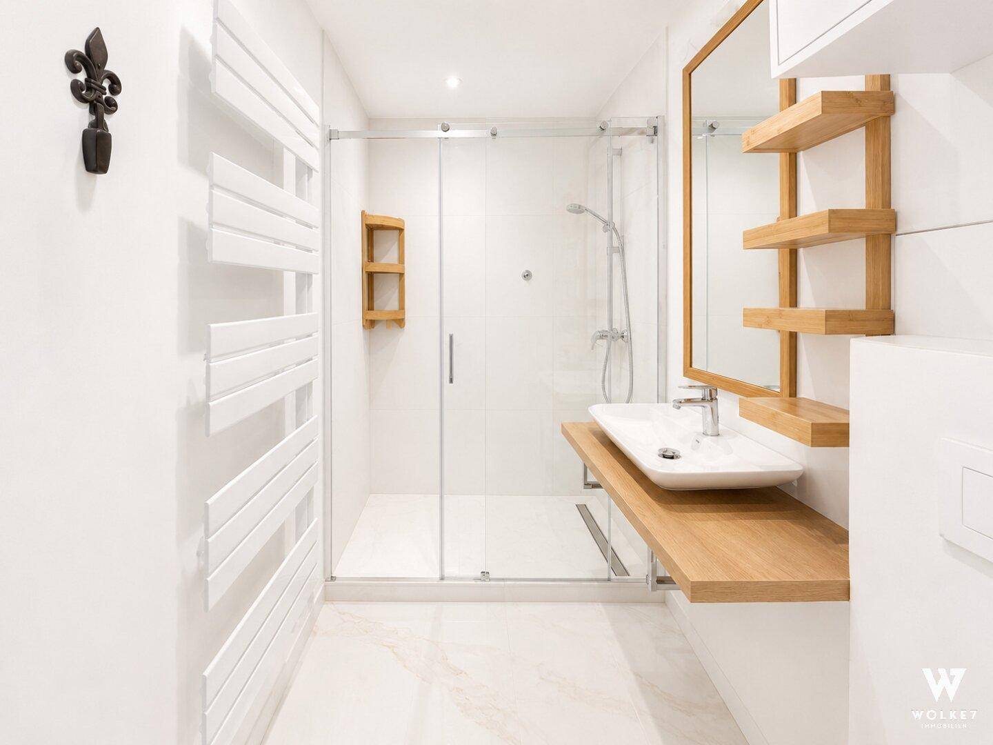 Helles Badezimmer mit moderner Dusche, Holzregalen und weißem Fliesenboden.