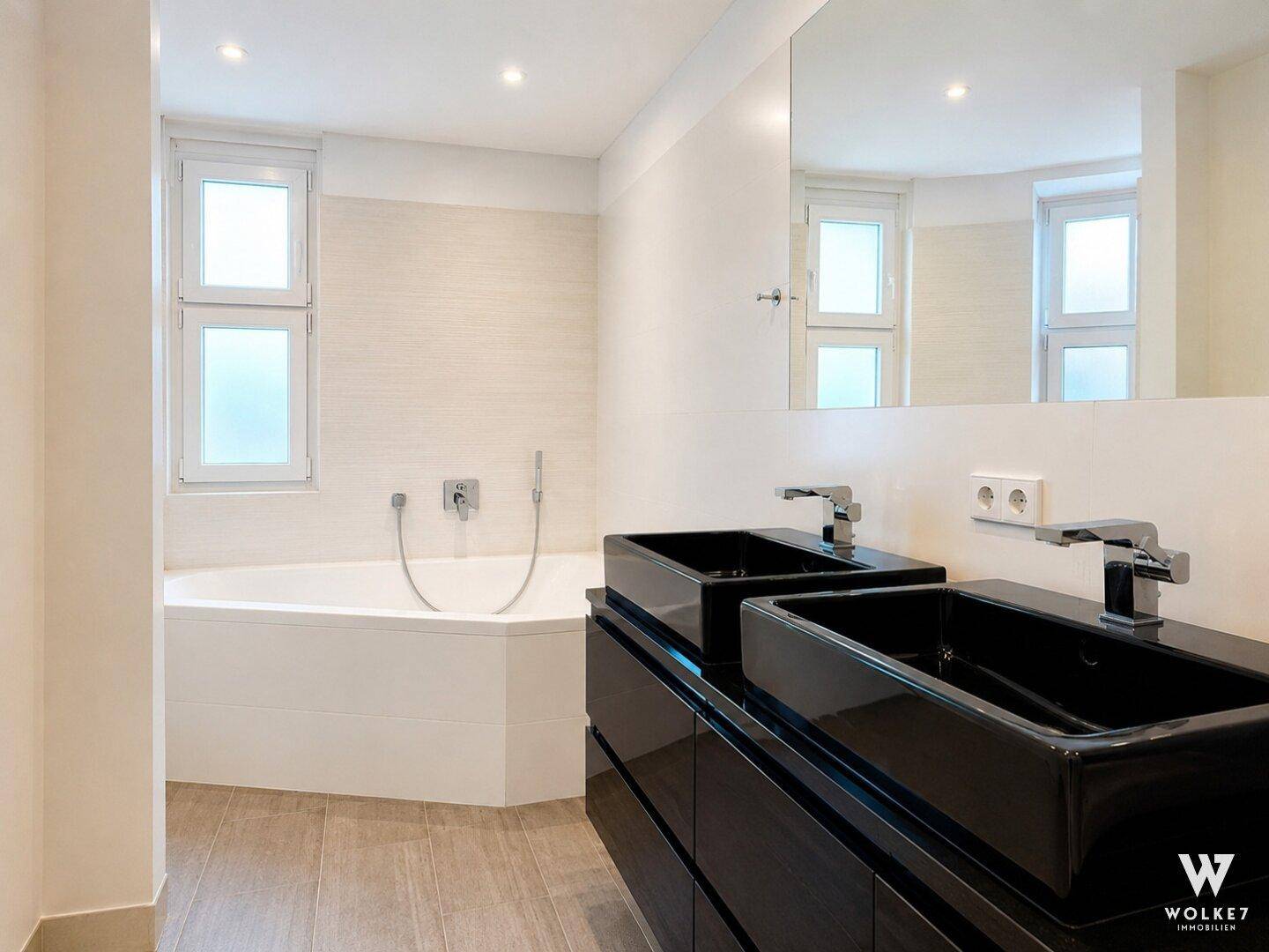 Modernes Badezimmer mit Eckbadewanne, Doppelwaschbecken und großen Spiegeln.