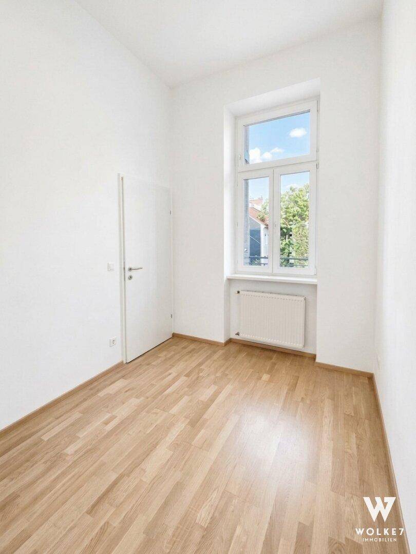 Kleineres, helles Zimmer mit Holzboden, weißen Wänden und einem Fenster, ideal als Schlaf- oder Arbeitszimmer.