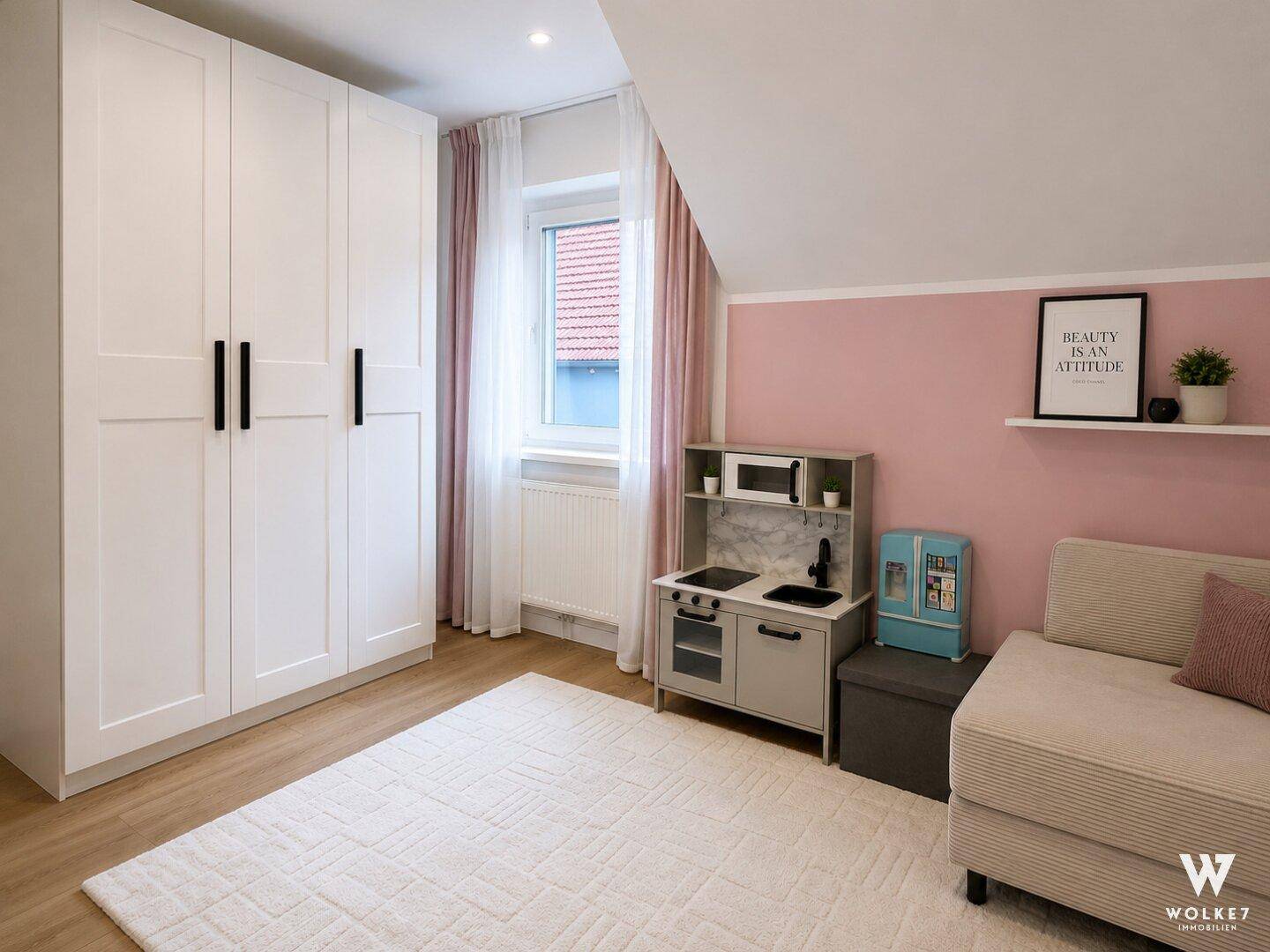 Kinderzimmer mit Spielküche, Sofa, Kleiderschrank und rosa Akzentwand.