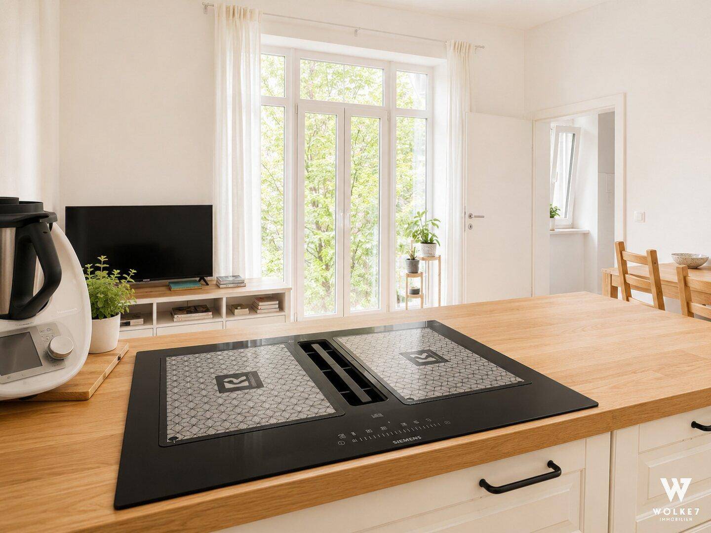 Moderne Kücheninsel mit integriertem Induktionskochfeld und Dunstabzug, umgeben von hellem Tageslicht.