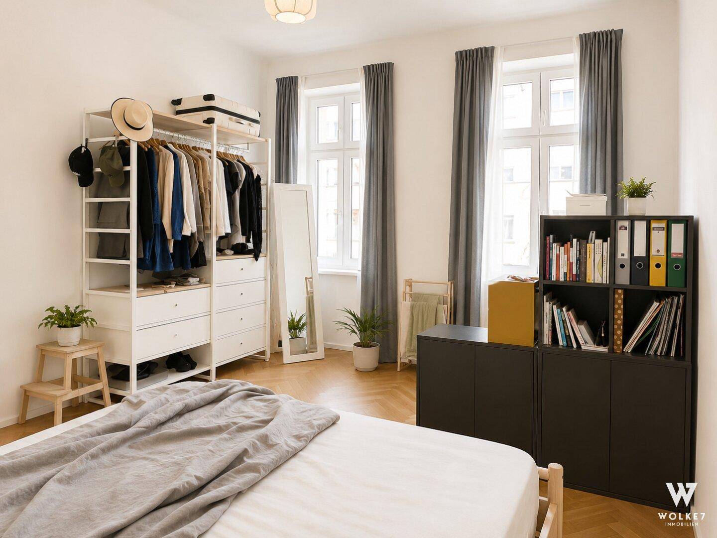 Geräumiges Schlafzimmer mit Holzboden, offenem Kleiderschrank und viel Stauraum.