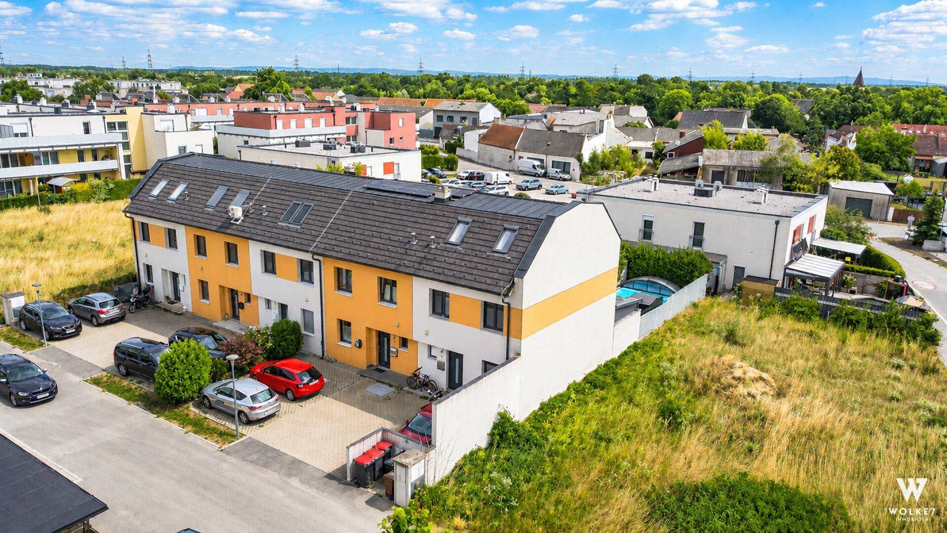 Überblick über die Reihenhäuser mit Parkplätzen und der umliegenden Wohngegend.