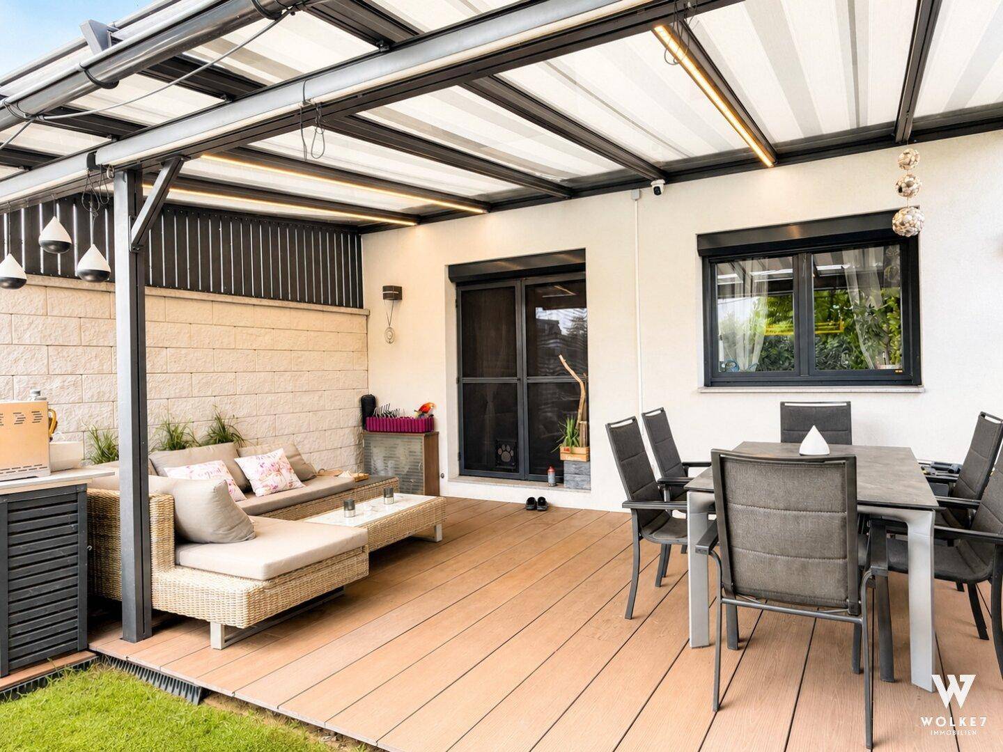Überdachte Terrasse mit Essbereich und Lounge-Möbeln, ideal für entspannte Stunden.