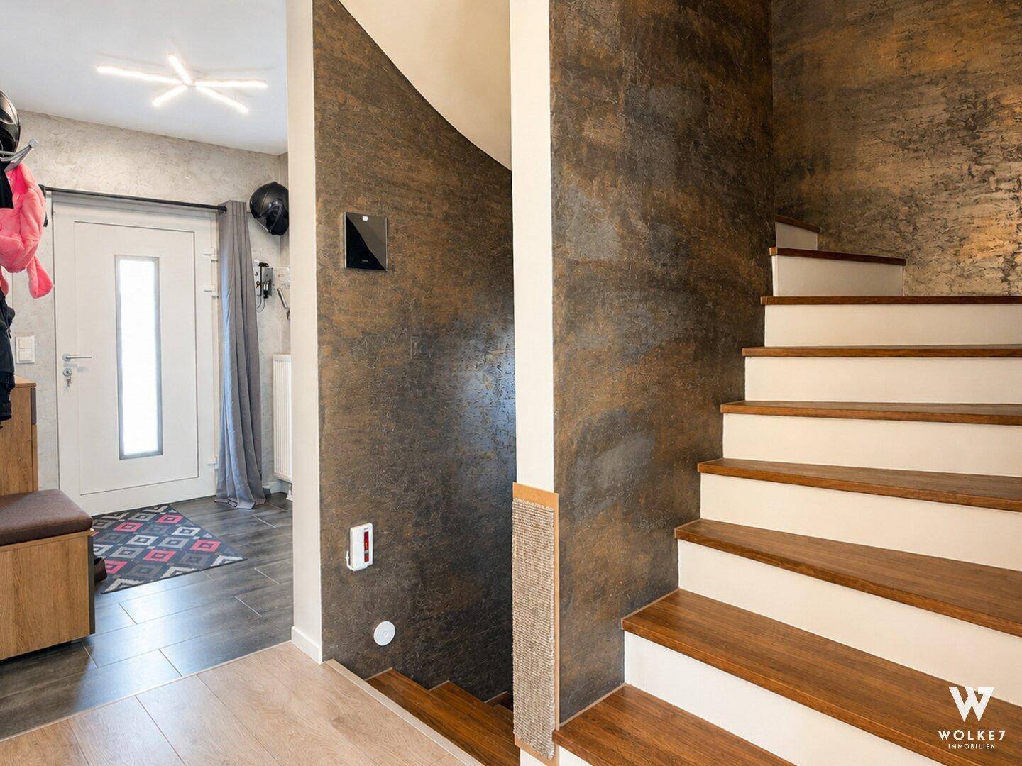 Moderner Eingangsbereich mit Treppe und dekorativer Wandgestaltung.