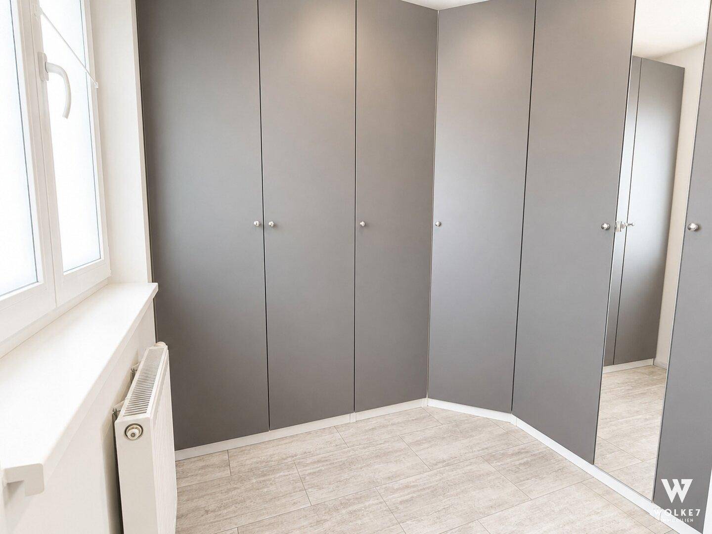 Begehbarer Kleiderschrank mit Einbauschränken und Fenster für Tageslicht.