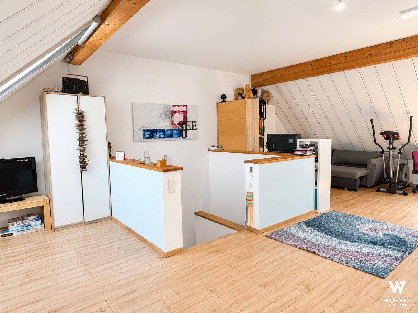 Geräumiges Dachgeschoss mit Holzbalken, Dachfenstern und offenem Wohnbereich.