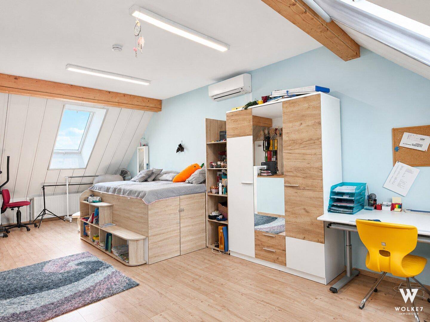 Helles Dachgeschosszimmer mit Schrägen, Dachfenstern und integriertem Bett.