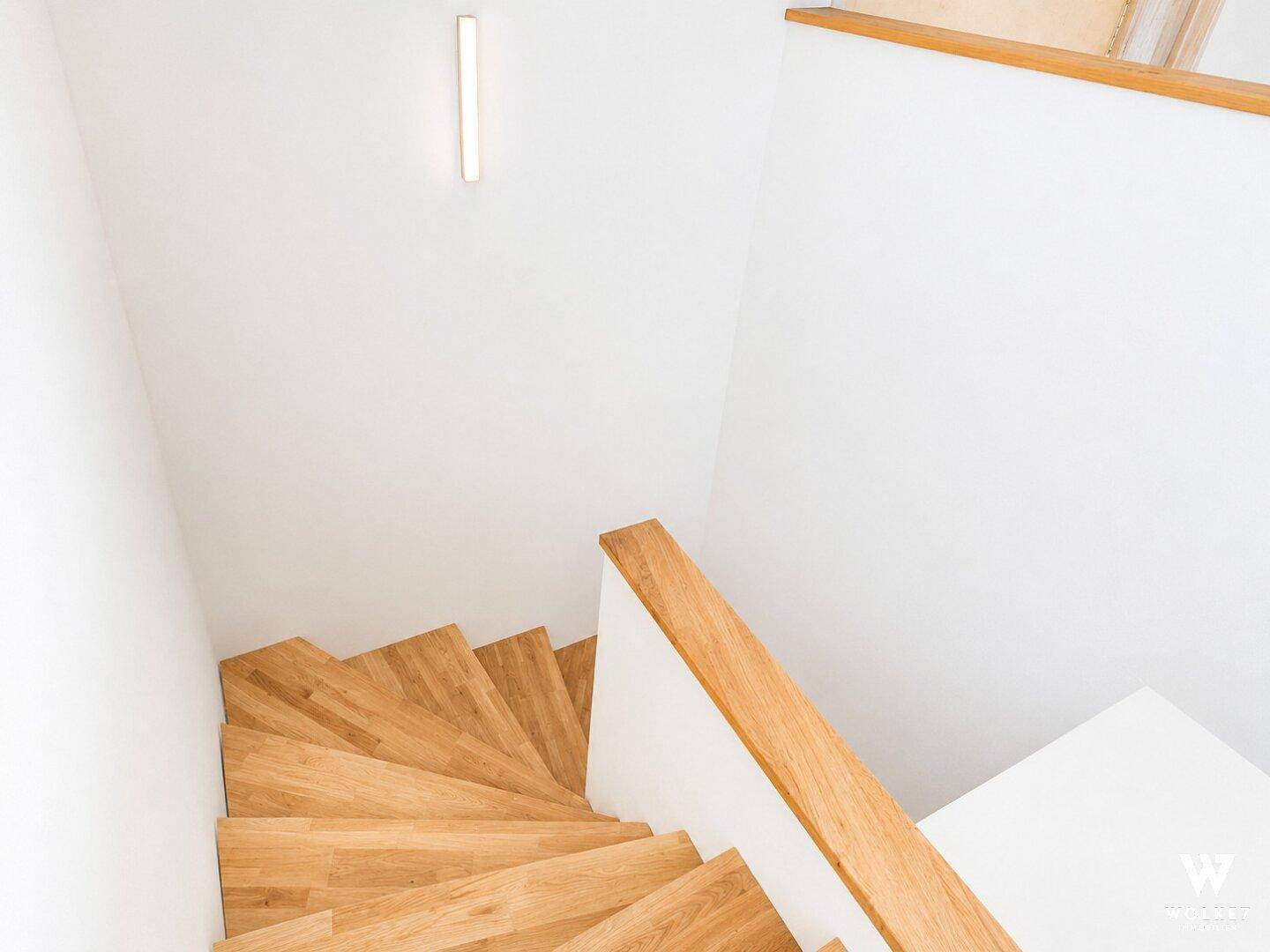 Holztreppe mit hellem Geländer, die die verschiedenen Etagen verbindet.