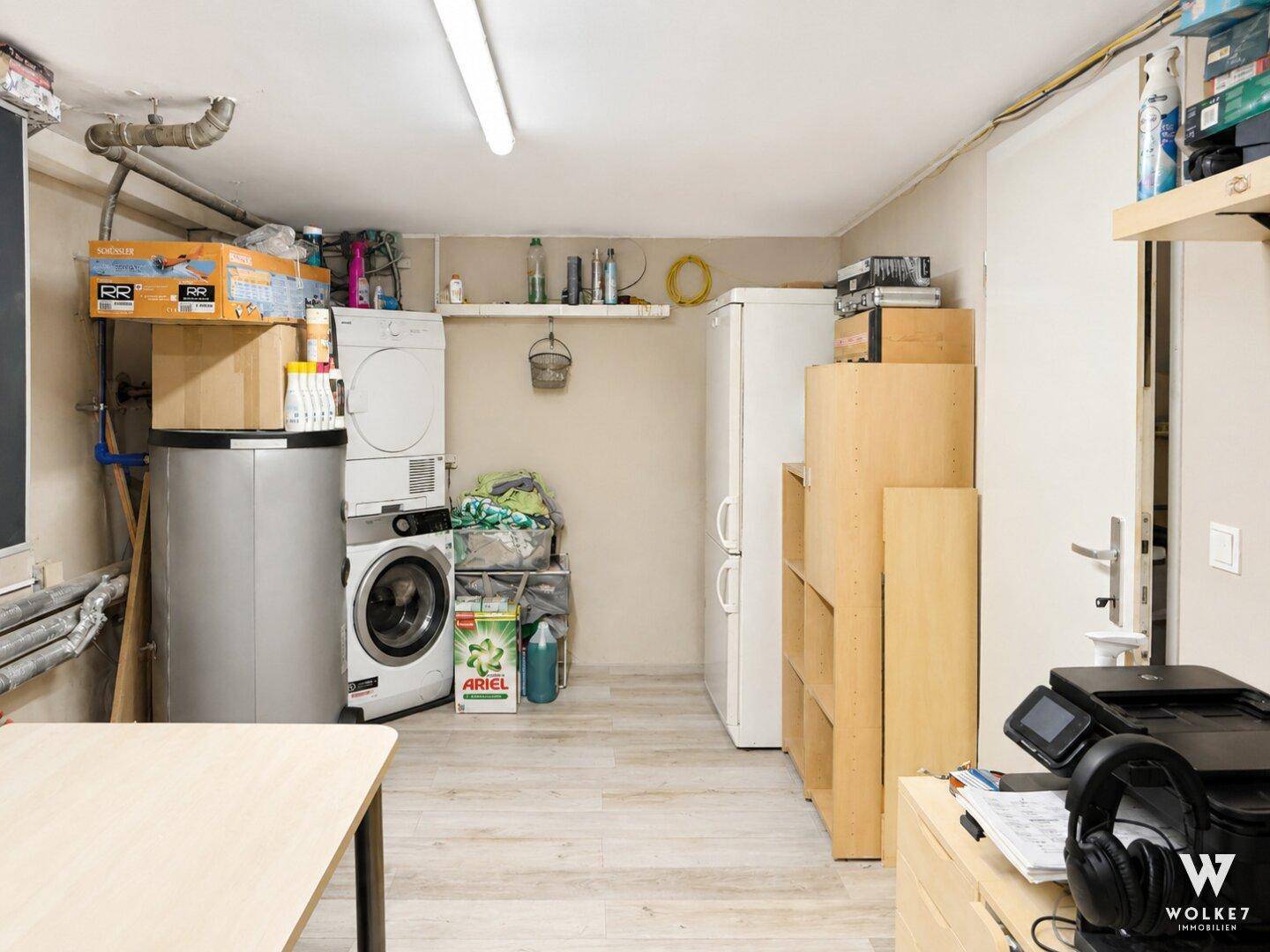 Geräumiger Hauswirtschaftsraum mit Waschmaschine, Trockner, Kühlschrank und viel Stauraum.