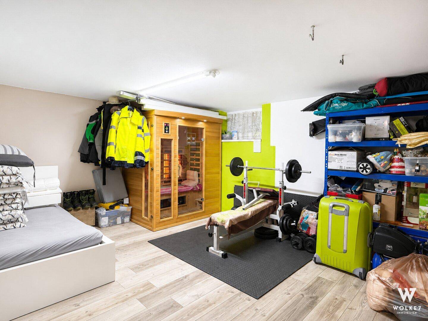 Fitnessbereich im Keller mit Hantelbank, Gewichten und einer modernen Infrarotsauna zur Entspannung.