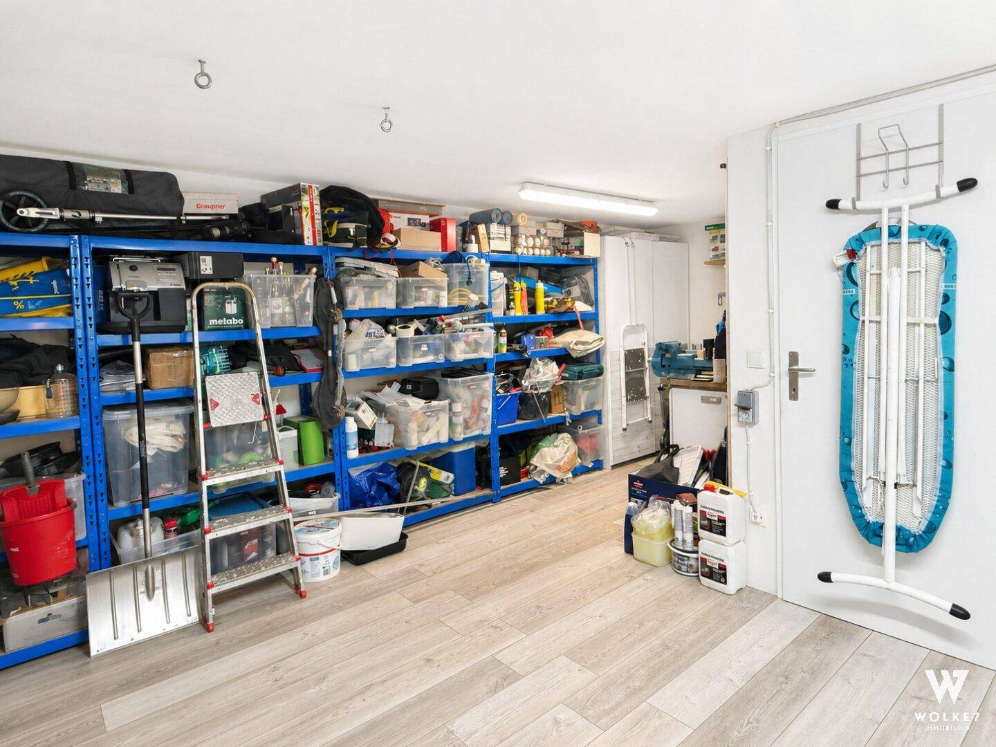 Großer Abstellraum mit blauen Regalen, die viel Platz für diverse Haushaltsgegenstände bieten.