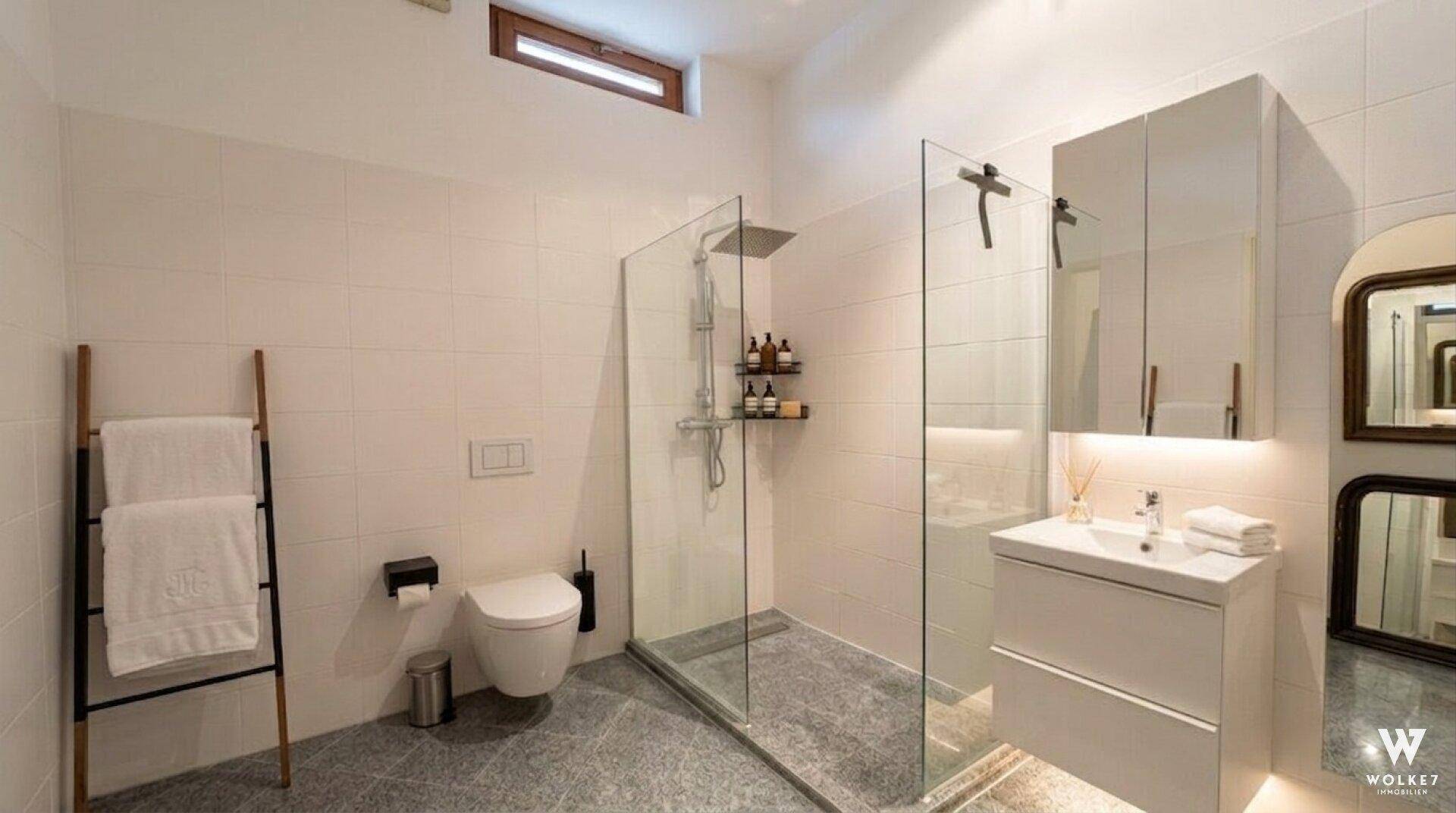 Modernes Badezimmer mit begehbarer Dusche, wandhängendem WC und Waschtisch mit Spiegelschrank.