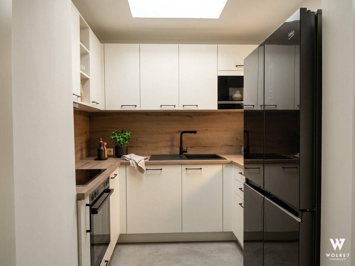 Moderne Küche mit weißen Schränken, Holzarbeitsplatte und schwarzem Kühlschrank.