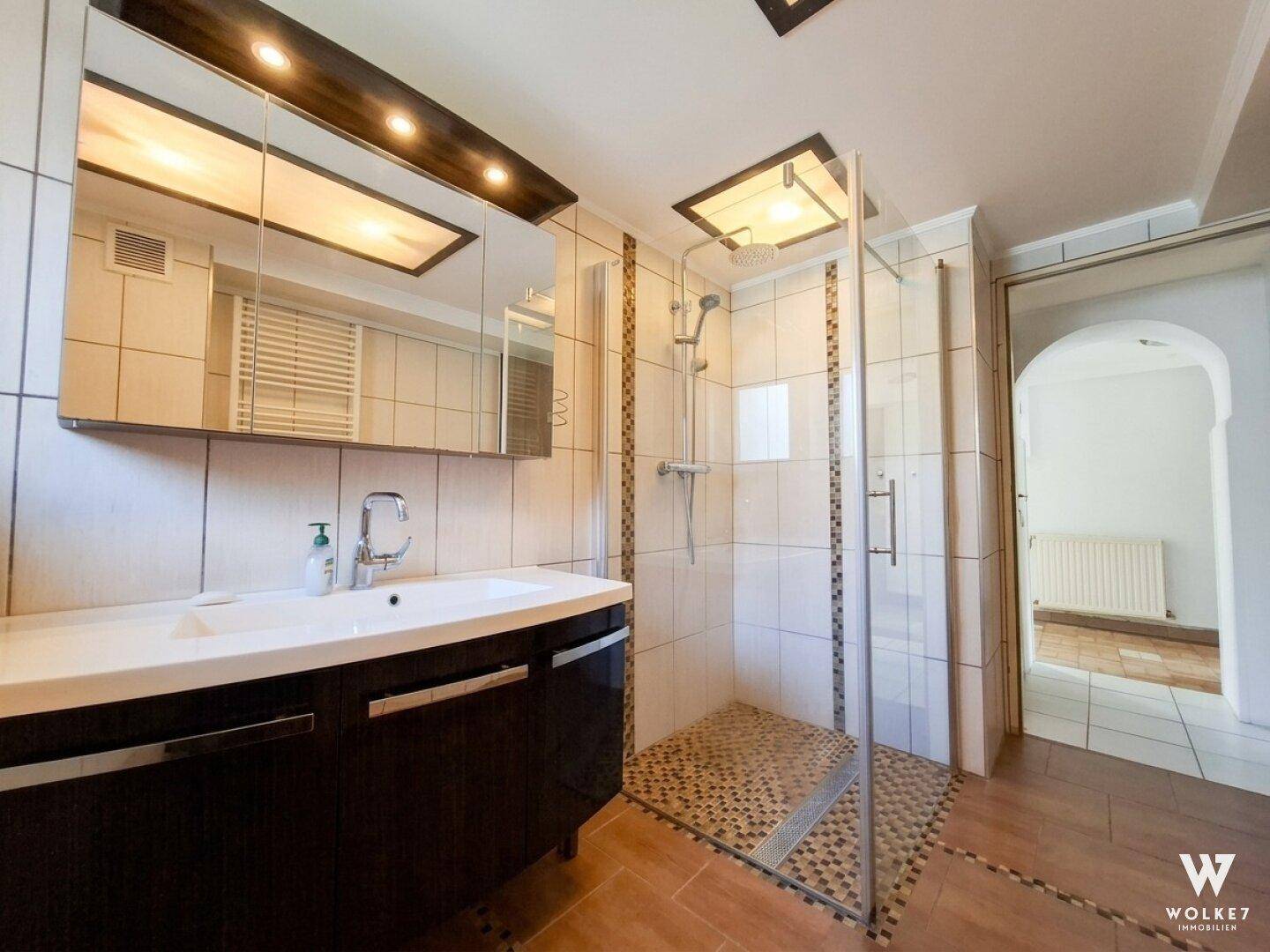 Modernes Badezimmer mit Duschkabine, Einzelwaschbecken und Spiegelschrank.