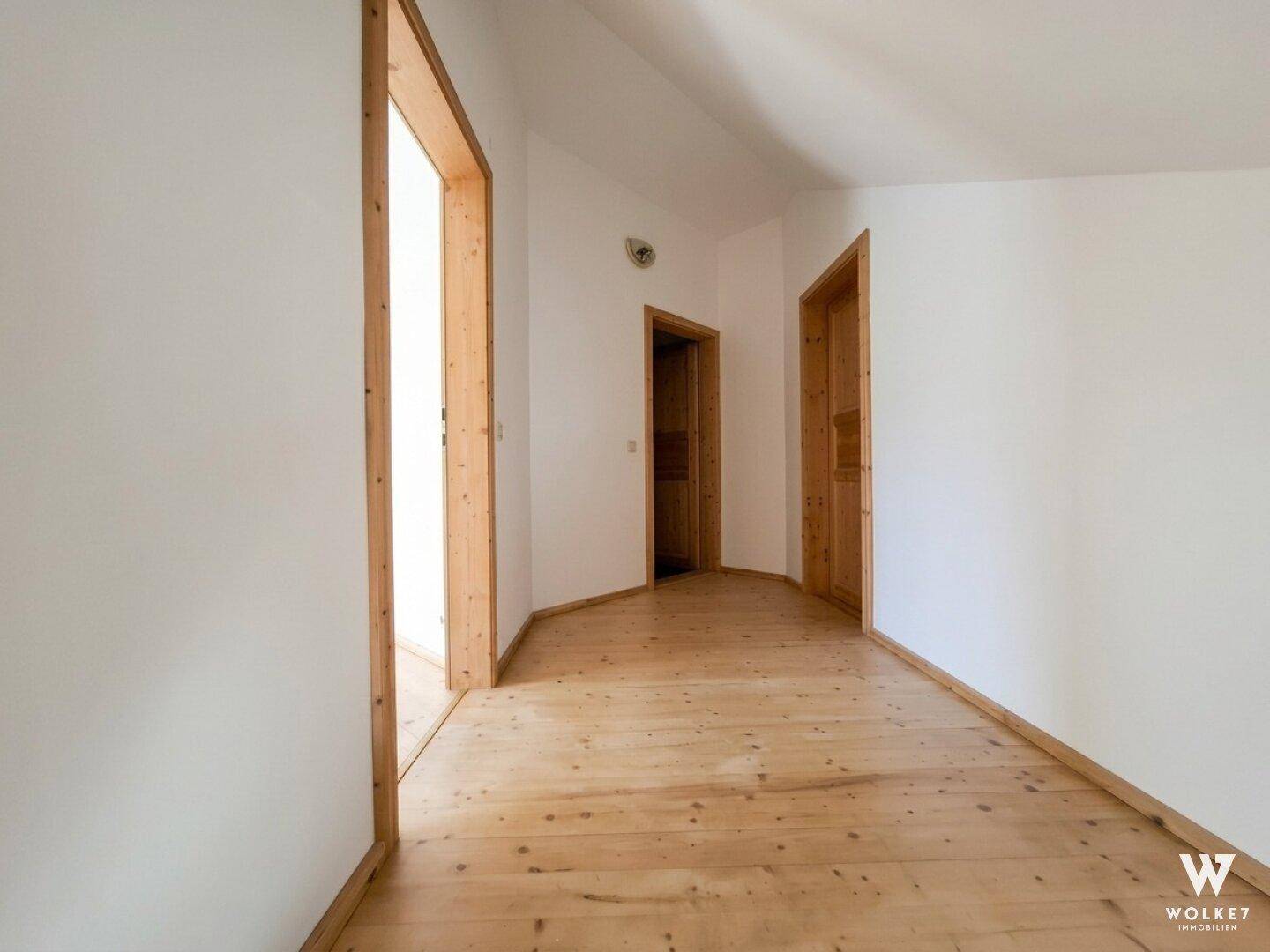 Heller Flur mit Holzboden und Holztüren, der zu weiteren Räumen führt.