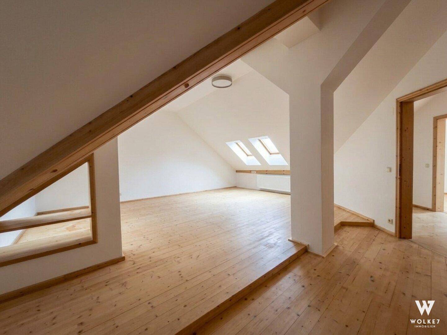 Großes Dachzimmer mit Holzboden, Dachfenstern und offener Raumgestaltung.