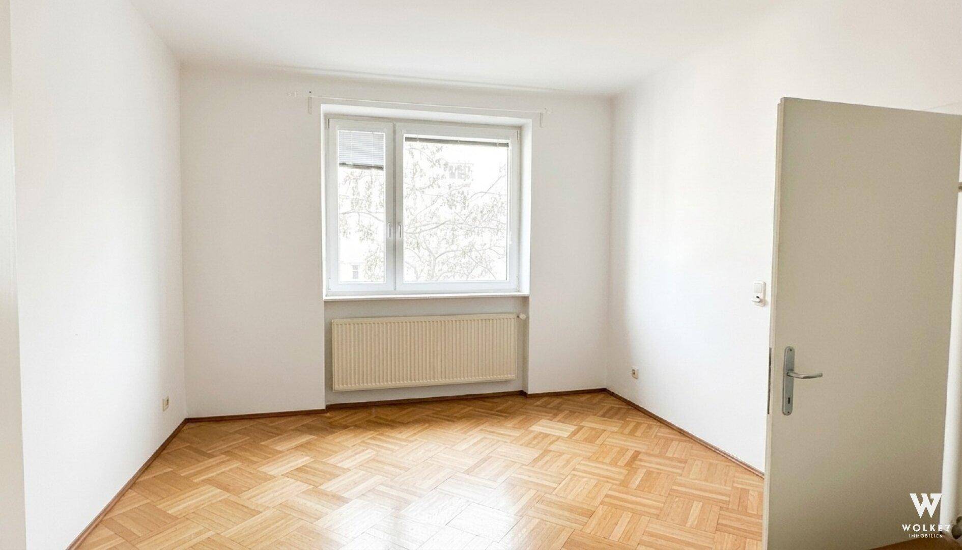 Leerer Raum mit Parkettboden und Fenster, bereit für neue Einrichtungsideen und Nutzung.
