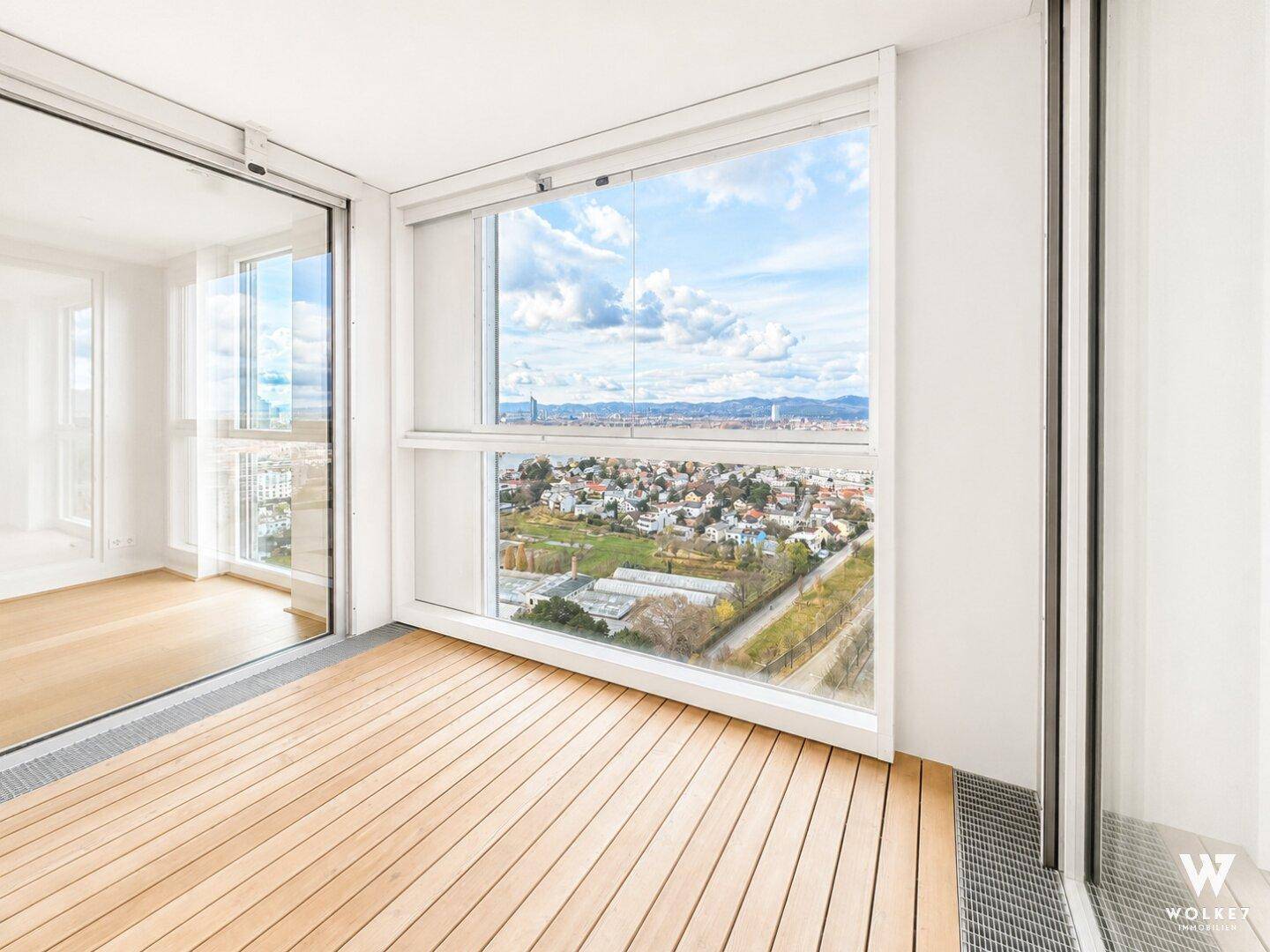 Verglaste Loggia mit Holzboden und weitem Panoramablick über die Stadt und die Landschaft.
