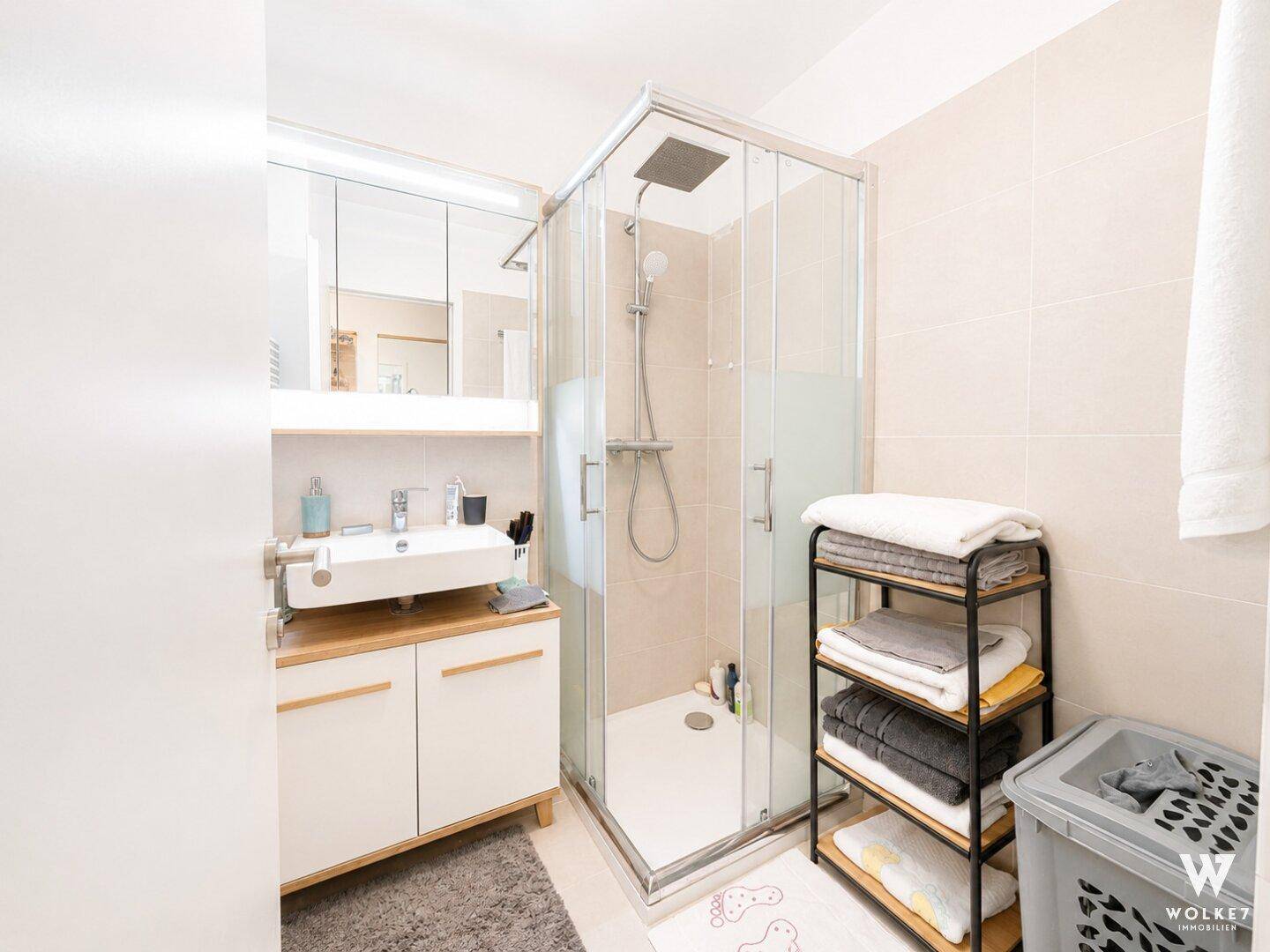 Modernes Badezimmer mit Duschkabine, Einzelwaschbecken und Spiegelschrank.