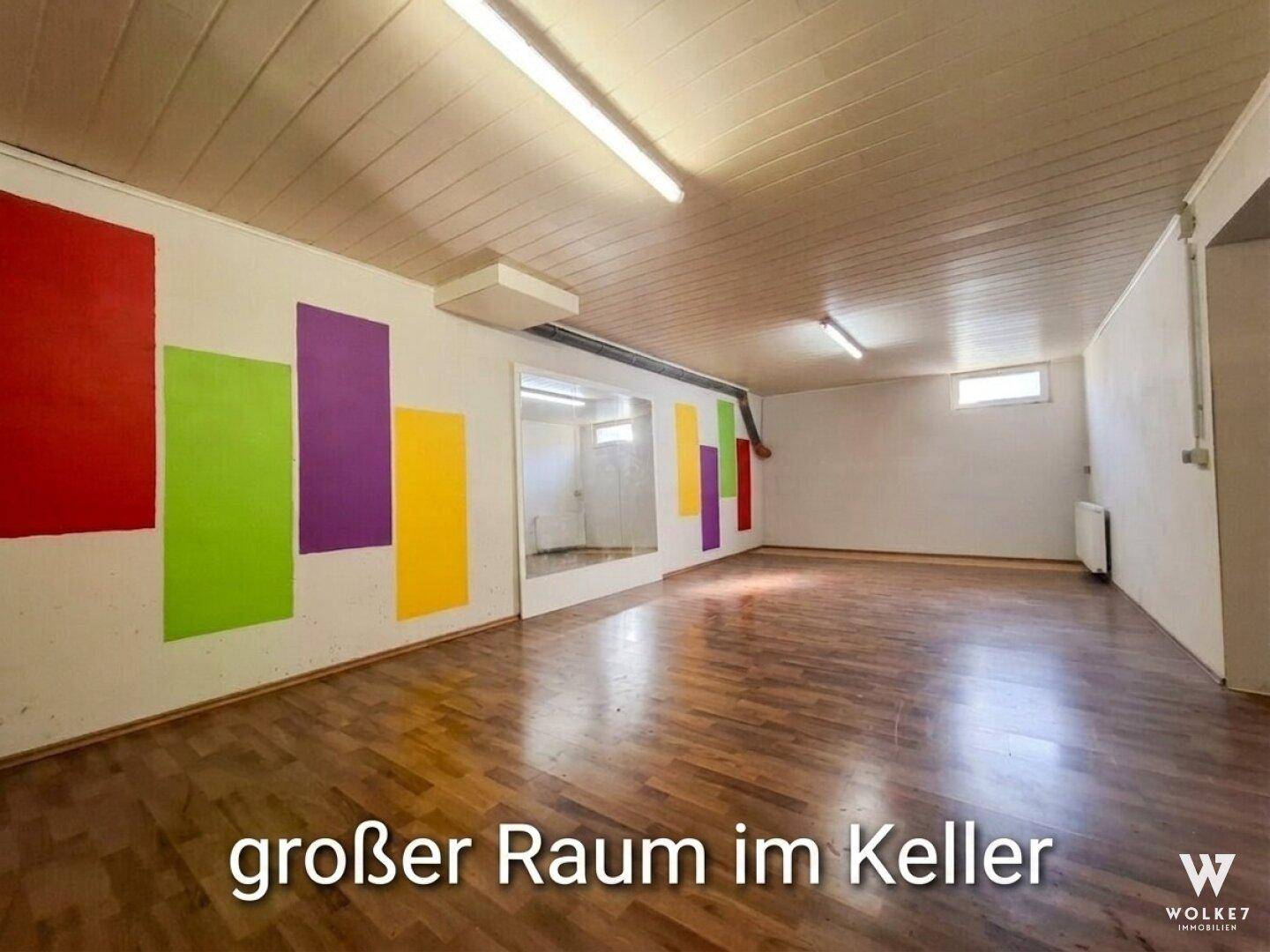 Großer Kellerraum mit Holzboden und bunten Wandakzenten, ideal für Hobbys.