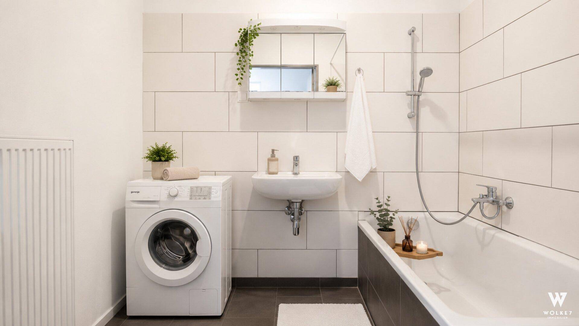 Modernes Badezimmer mit Badewanne, Waschbecken und Waschmaschine, hell gefliest.