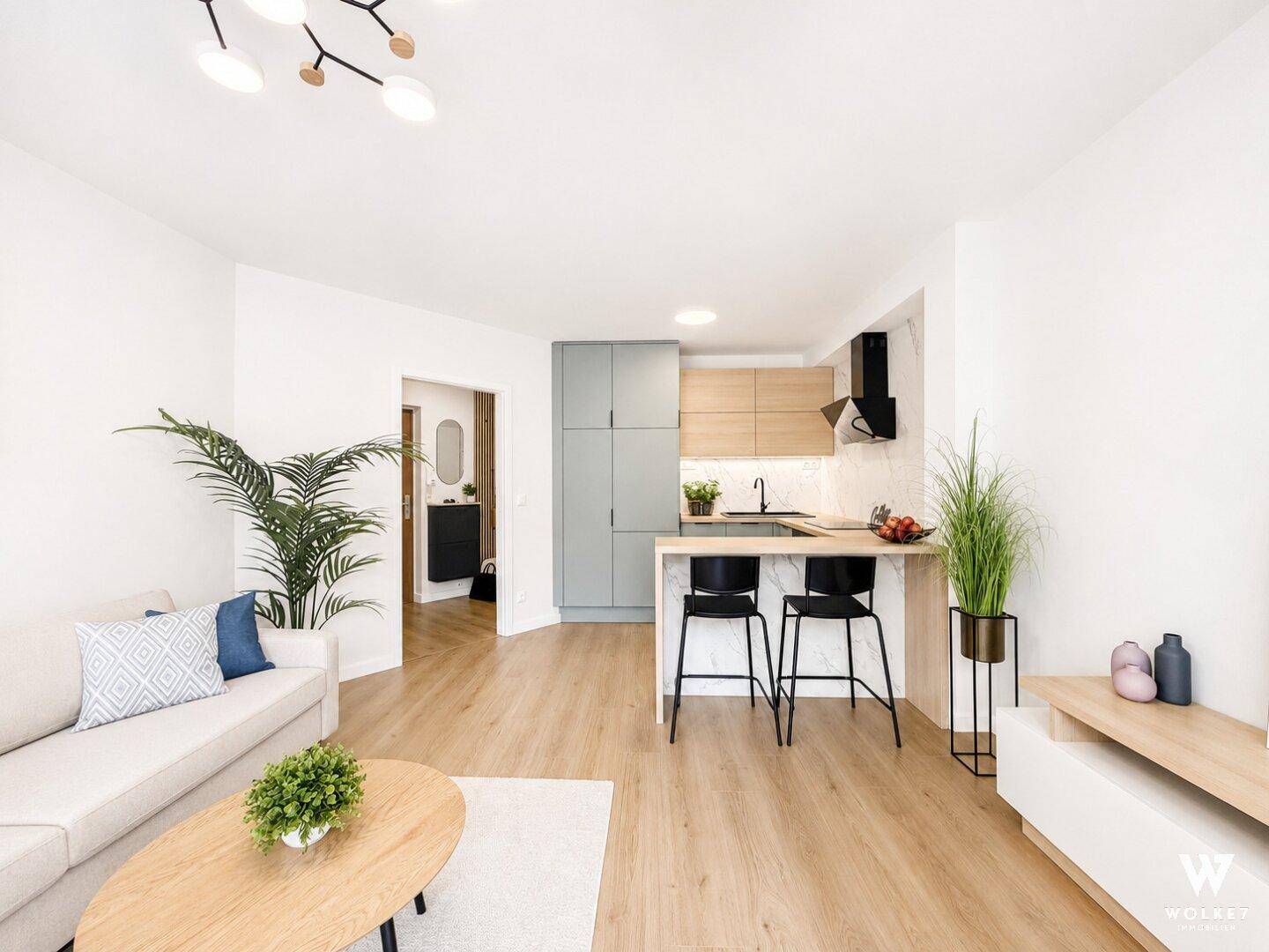 Moderner offener Wohnbereich mit integrierter Küche, Holzboden und gemütlichem Sofa.