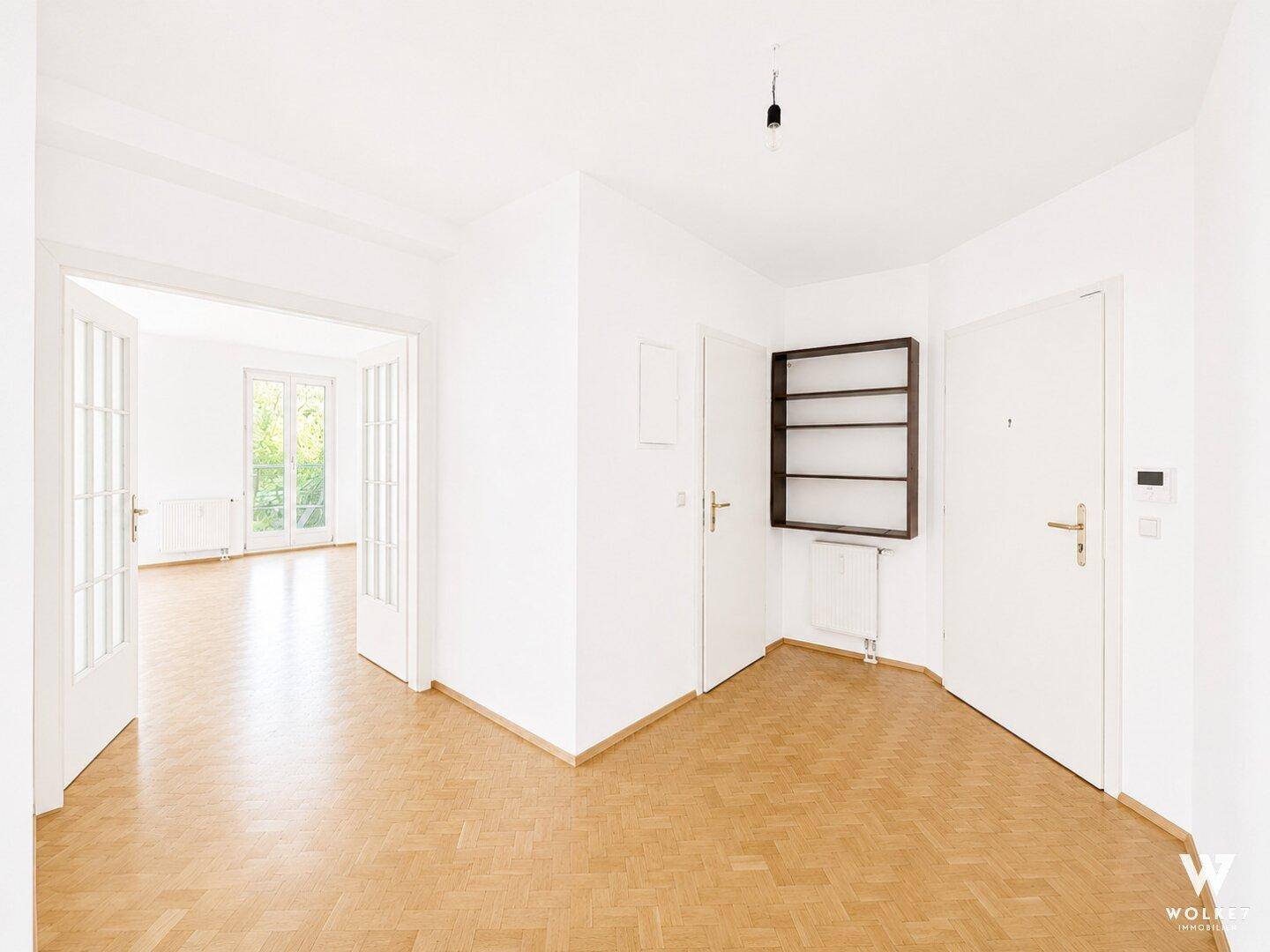 Heller Flurbereich mit Parkettboden und Doppeltüren, die zu einem weiteren Zimmer führen.