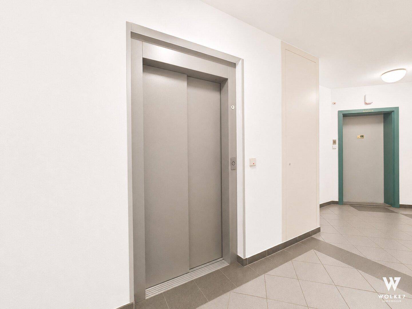 Moderner Aufzug in einem hellen Flur mit Fliesenboden, der Zugang zu den Etagen bietet.