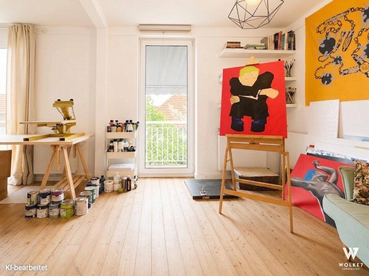 Kreativer Arbeitsraum mit Holzboden, großen Fenstern und Zugang zu einem französischen Balkon.