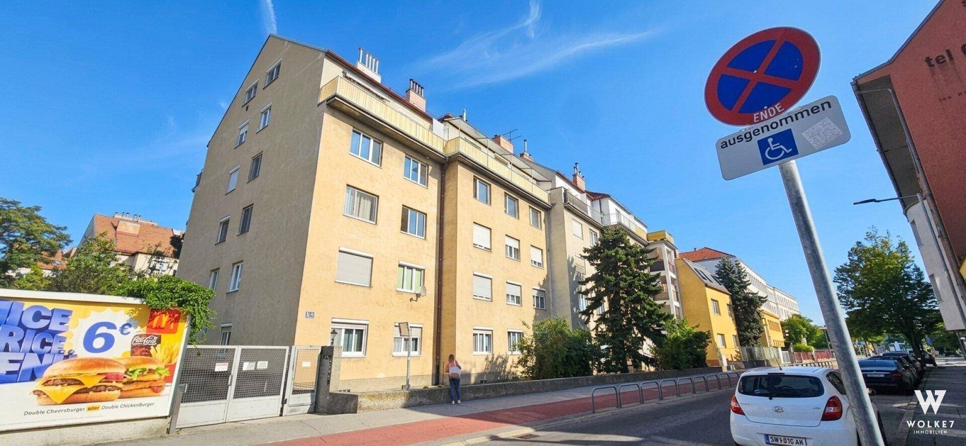 Mehrstöckiges Wohngebäude mit klassischer Fassade und Fenstern zur Straße.