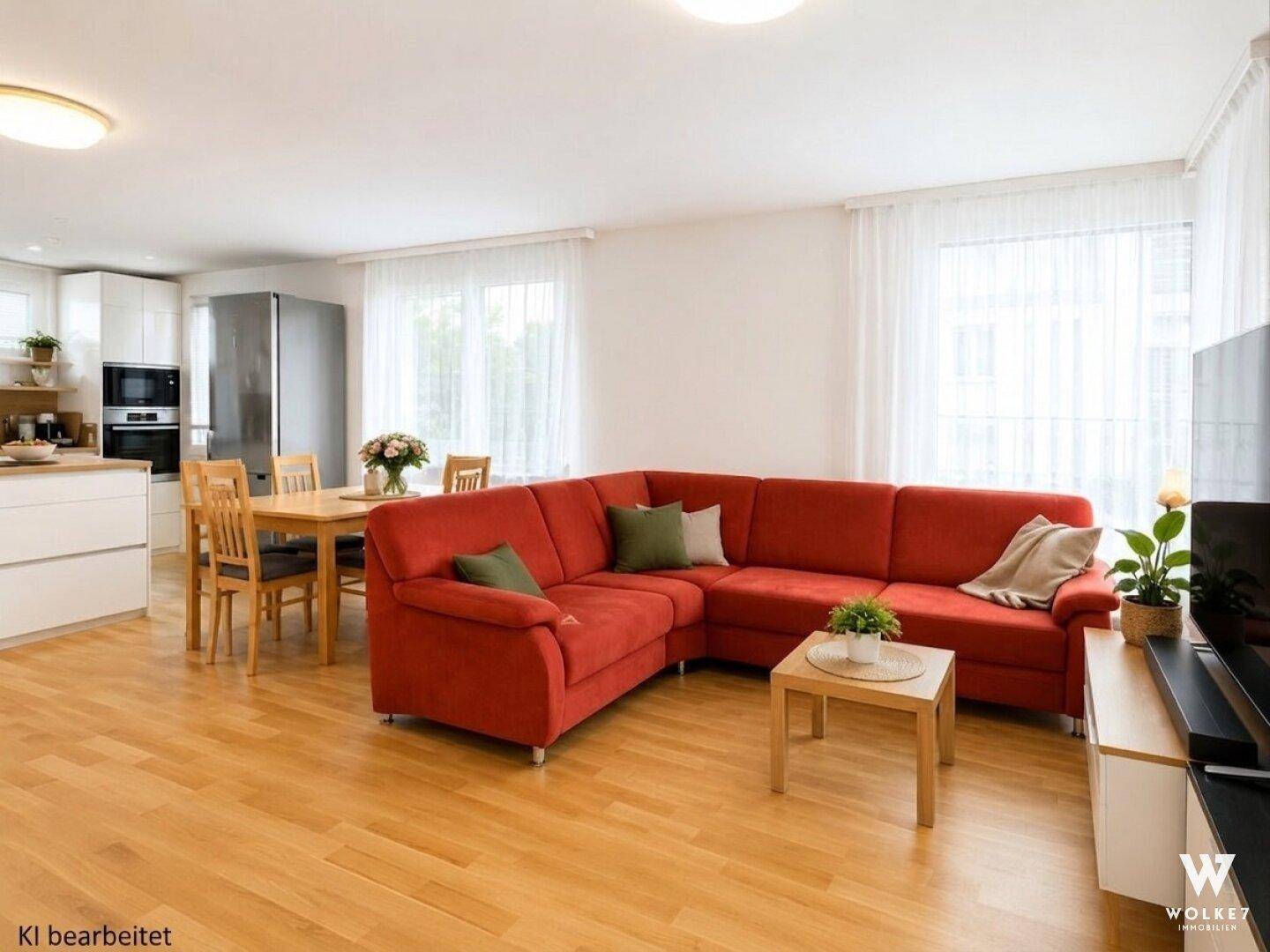 Heller offener Wohn- und Essbereich mit integrierter Küche und rotem Ecksofa.