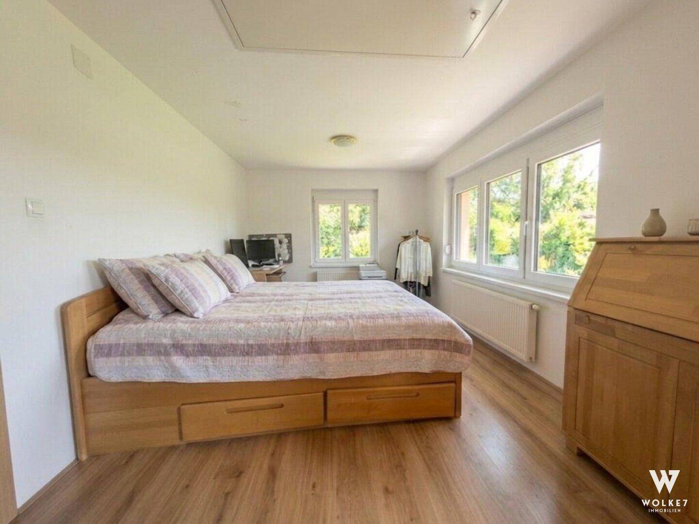 Gemütliches Schlafzimmer mit Holzbett, Schreibtisch und Blick ins Grüne.