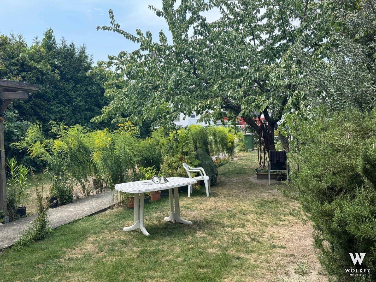 Gemütlicher Gartenbereich mit Tisch und Stühlen unter einem Baum, ideal zum Entspannen im Freien.