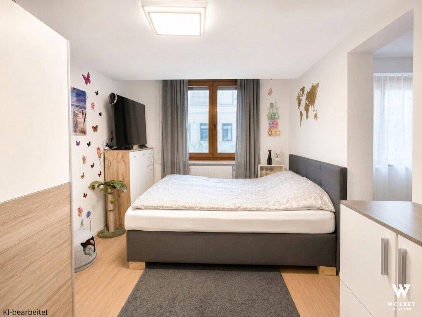 Gemütliches Schlafzimmer mit grauem Bett, Laminatboden und modernem Dekor an den Wänden.