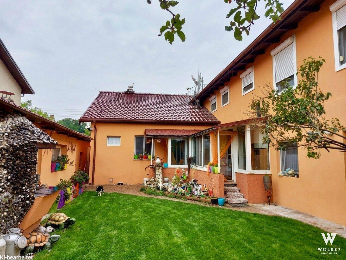 Rückseite des Hauses mit kleinem Garten, Wintergarten und bunten Dekorationen im Außenbereich.