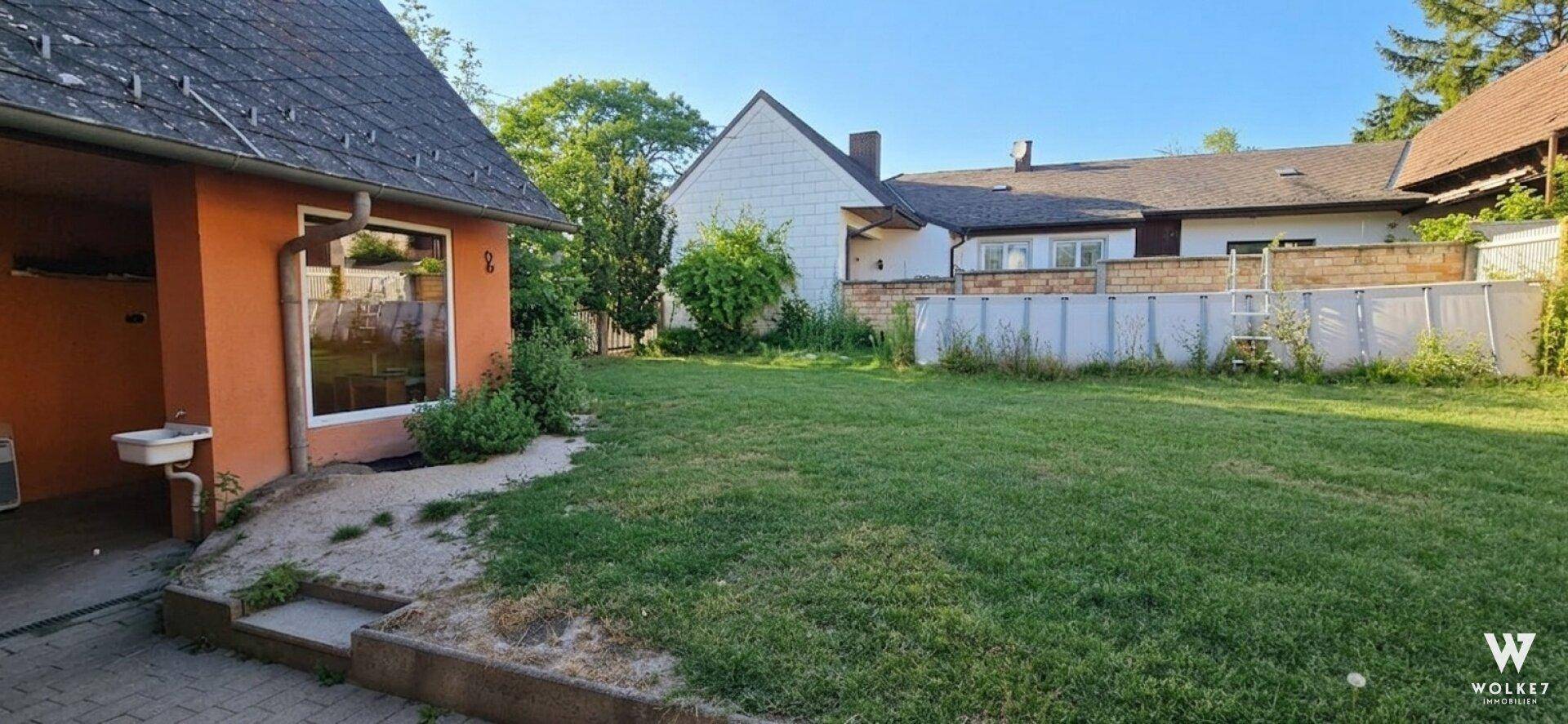 Großer Garten mit Rasenfläche und einem Aufstellpool im hinteren Bereich des Grundstücks.